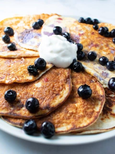 coconut pancakes on a white plate with blueberries