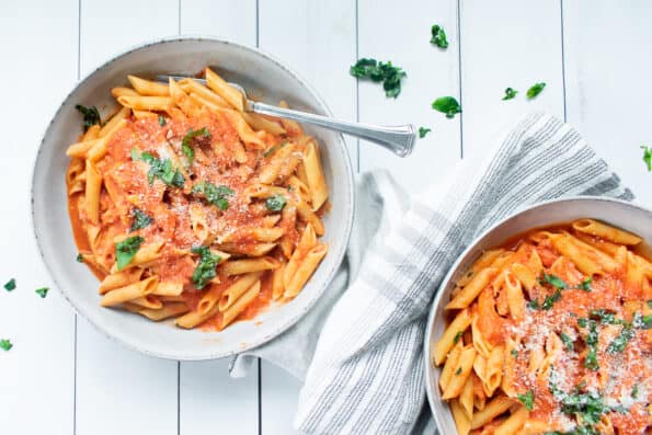 penne with vodka sauce in two white bowls on a gray towel