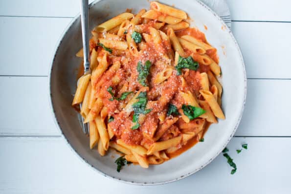 penne with vodka sauce in a white bowl on a gray towel