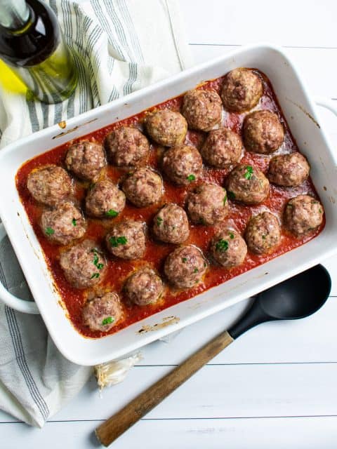meatballs in a white baking dish in tomato sauce