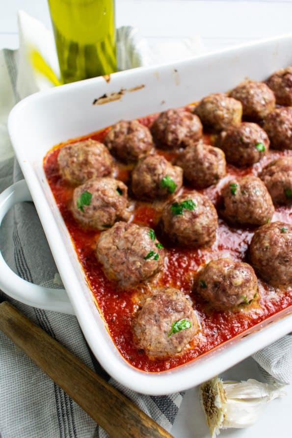 meatballs in a white baking dish in tomato sauce