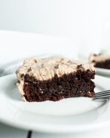 chocolate cake with chocolate icing sitting on a white plate with fork