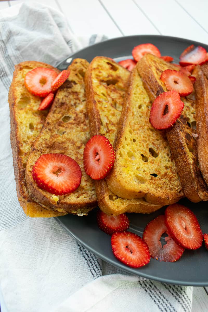 french toast slices layered on a plate with strawberry slices