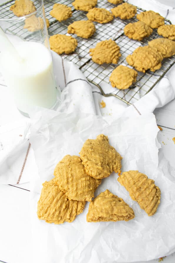 peanut butter cookies on white parchment paper with glass of milk
