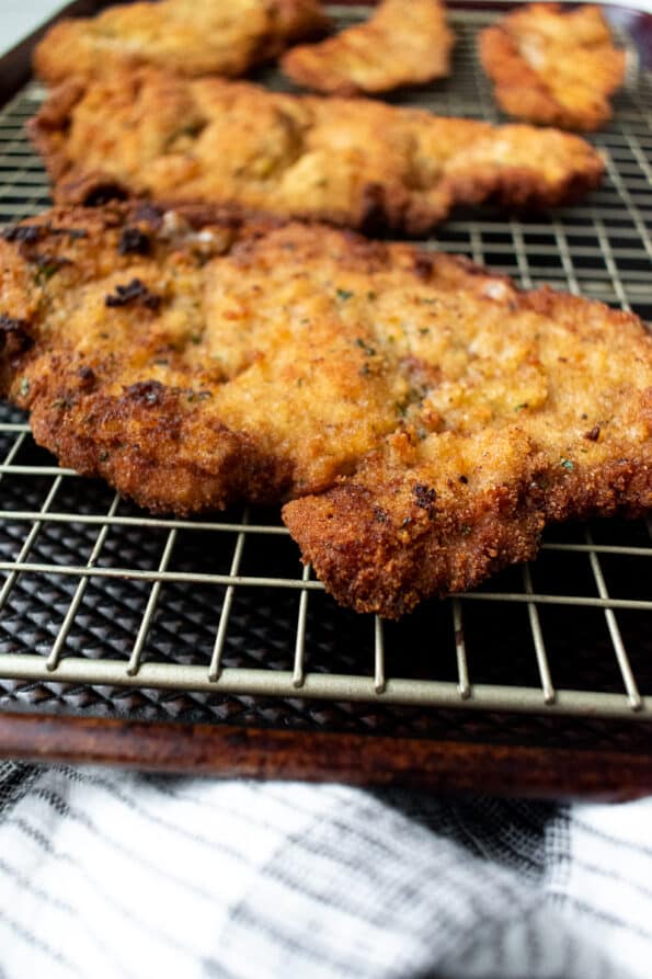 close-up of veal cutlets on cooling rack and baking sheet